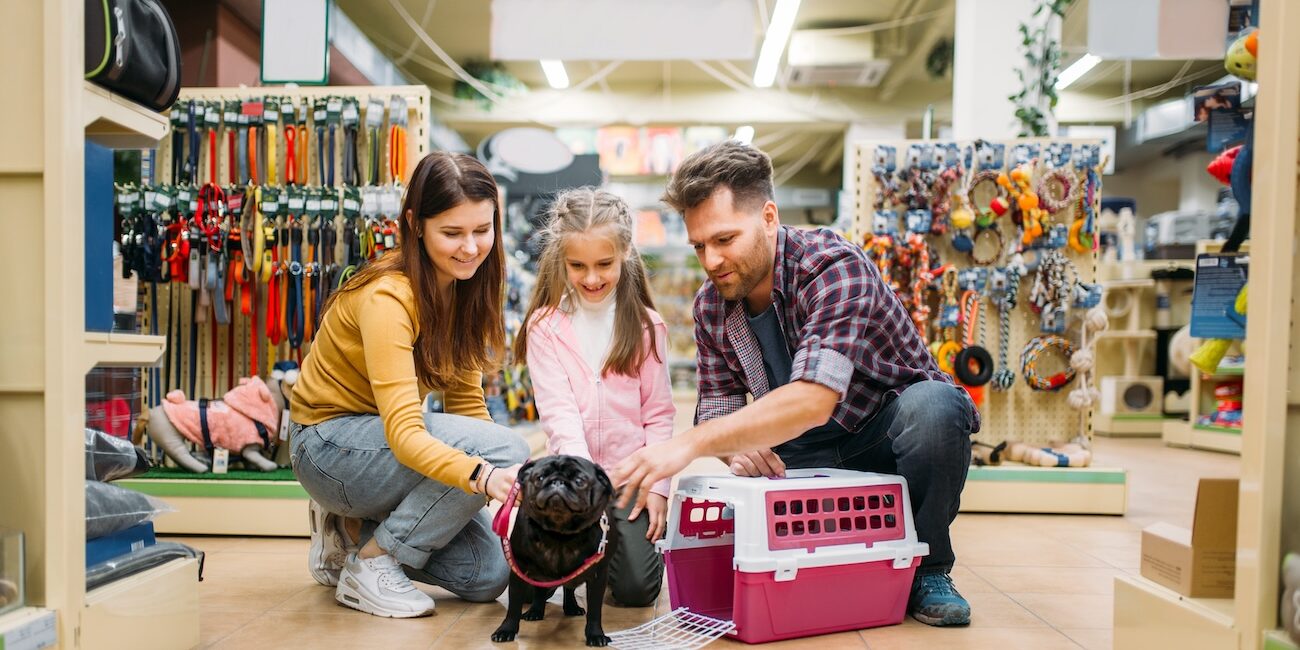 Family buying supplies for little puppy in petshop Family buying supplies for little puppy in petshop. Father, mother and dauther chooses accessories for dog in pet shop
